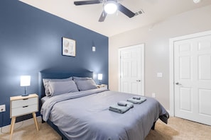 A bedroom with a bed, bedside tables, a ceiling fan, and white doors. - Grand Prairie 2BR | IKEA, Epic Waters, Bass Pro (Grand Prairie)