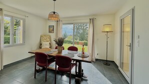 Comedor con mesa, sillas, lámpara colgante y vistas a zonas verdes.