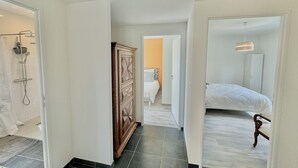 Habitación de hotel con ducha, armario, cama y un pasillo que conduce a otra habitación.