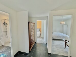 Ein Hotelzimmer mit Dusche, Schrank, Bett und einem zur anderen Kammer führenden Gang.