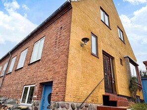 Un edificio a due piani con facciata in mattoni e una sezione gialla sulla destra.