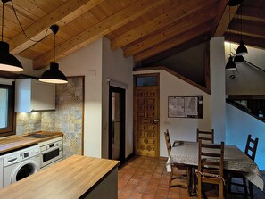 Una cocina con armarios de madera, lavadora y comedor con mesa y sillas.