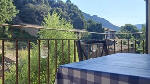 Un balcó amb vista a un paisatge de muntanyes, una taula amb estovell de petons i una cadira.