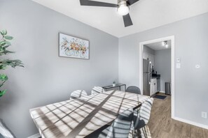 Eine moderne Küche mit Kühlschrank, einem Esstisch mit Stühlen und einem Deckenventilator.