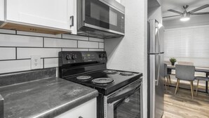 A modern kitchen with a black stove, stainless steel microwave, and white cabinets. - Arlington 3BR | AT&T, Globe Life, 6 Flags, Parking (Arlington)