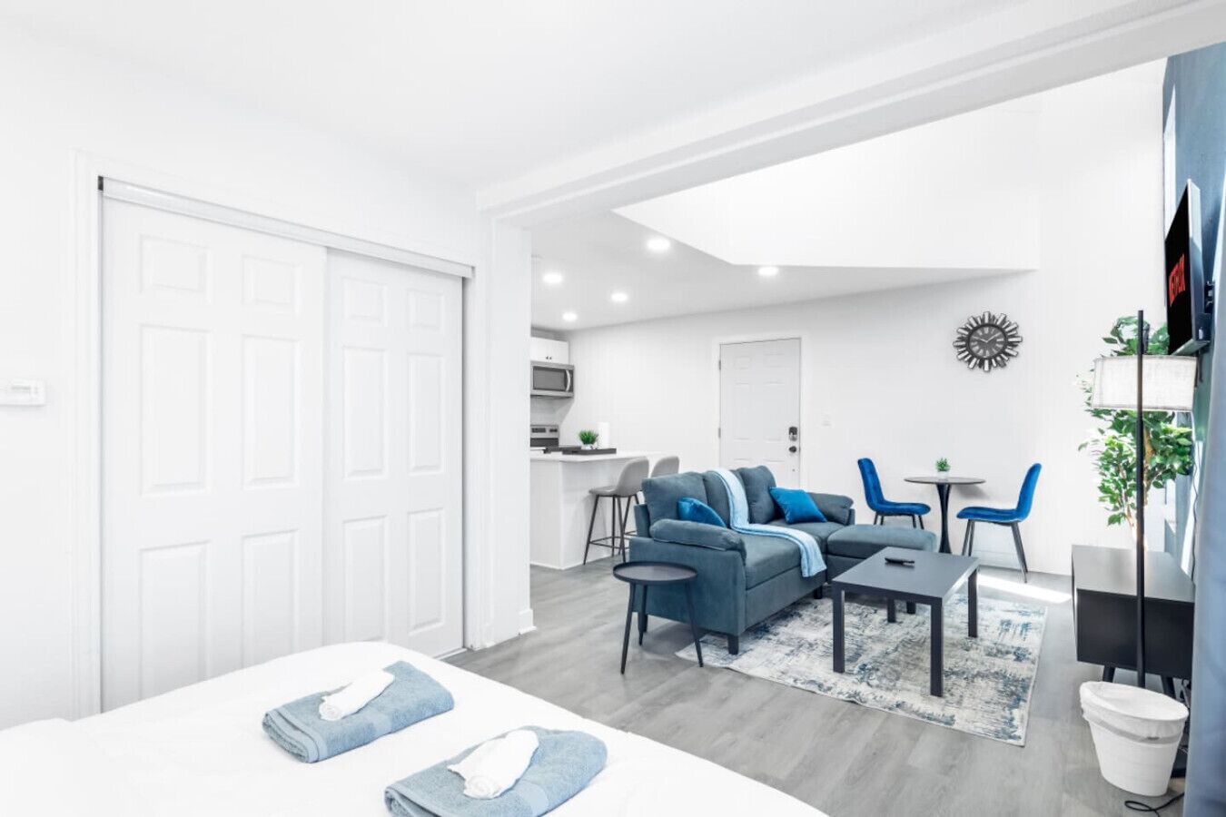 A modern apartment with a large bed, a sofa, a dining area, and a kitchen.