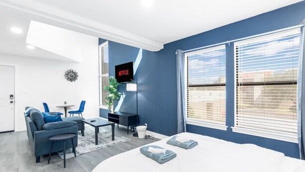 Et moderne hotelværelse med seng, skrivebord, stol, fjernsyn og store vinduer.
