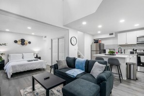 Een modern appartement met een woonkamer, een aparte slaapkamer, een kitchenette en een eethoek.