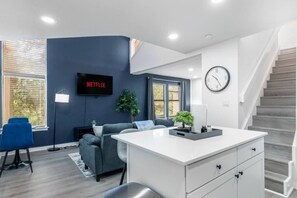 Een moderne woonkamer met een flatscreen televisie, een bank, een salontafel en een trap.