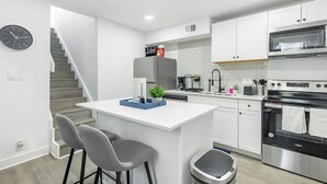 A modern kitchen with white cabinetry, a stainless steel oven, a microwave, and a built-in coffee maker. - 5 Min to Love Field | Gated+Guard | 2BR | Parking (Dallas)
