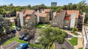 A residential complex with multiple apartment buildings, a parking lot, and green spaces. - 5 Min to Love Field | Gated+Guard | 2BR | Parking (Dallas)
