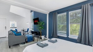 Una habitación de hotel moderna con una cama, un sofá, un escritorio y un televisor.