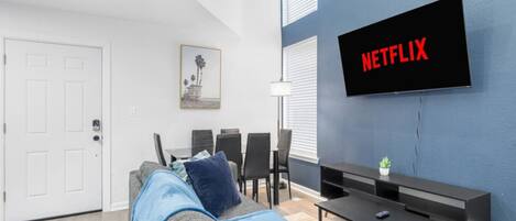 A modern living room with a sofa, TV, and dining area.