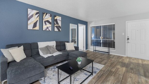 A living room with a gray sectional sofa, a black coffee table, and abstract wall art.