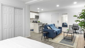 Ein modernes Apartment mit Küchenzeile, einer Couch, einem Esstisch und einem großen Fenster.