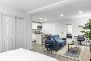 A modern apartment with a kitchenette, a sofa, a dining table, and a large window. - 5 Min to Love Field | Gated+Guard | 1BR | Parking (Dallas)