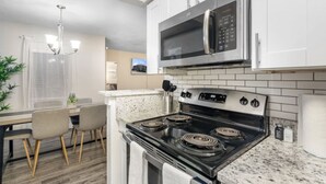 A modern kitchen with a stove, microwave, and white cabinets.
