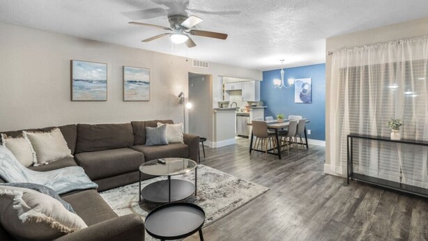 A living room with a sofa, coffee table, and a ceiling fan.