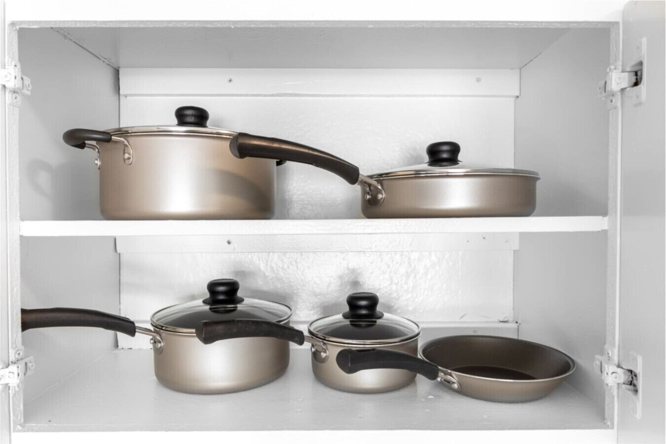 Un meuble de cuisine contenant des ustensiles de cuisine en acier inoxydable, notamment des casseroles et des poêles avec des poignées noires.