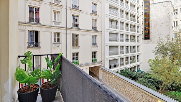 A multi-story building with balconies, potted plants, and a courtyard. - Beautiful Apartment 2br/6p - Eiffel Tower (Paris)
