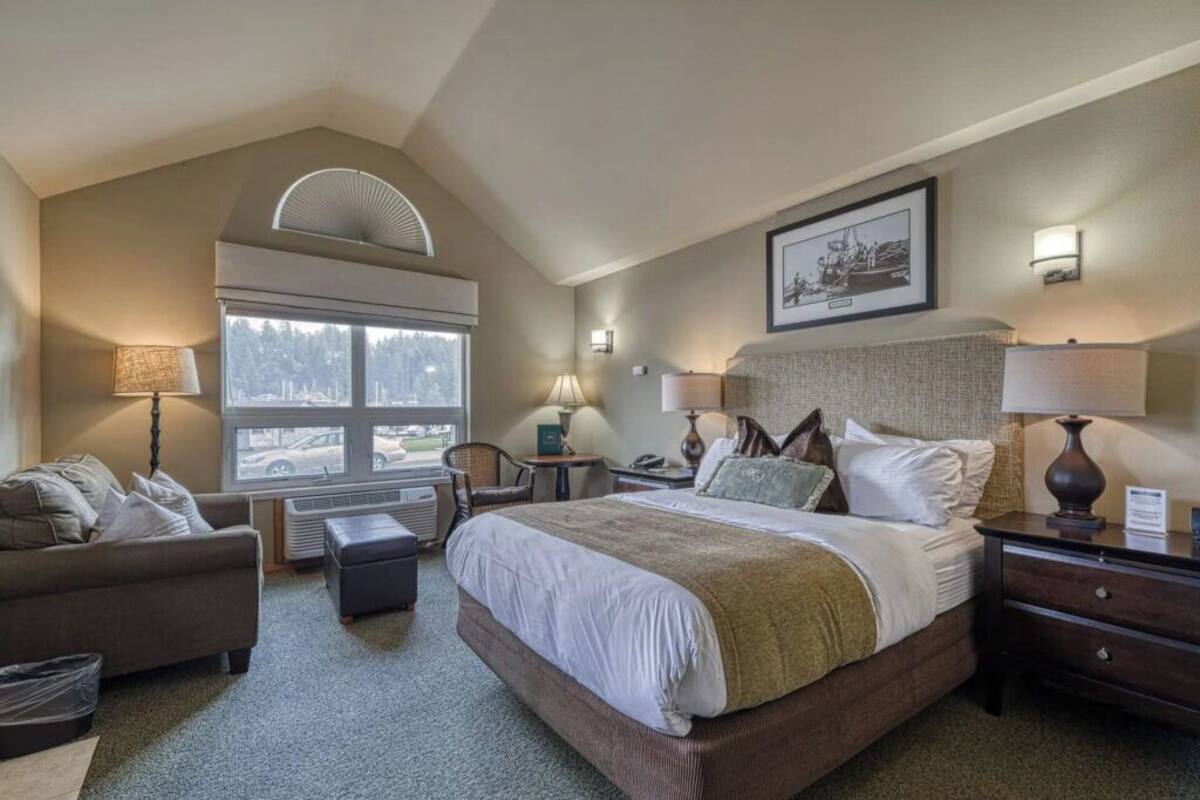 A hotel room with a large bed, a sofa, a chair, a desk, and a window with a view of the outside.