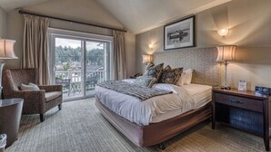 Une chambre d’hôtel avec un grand lit, une chaise, un bureau et un balcon avec vue.