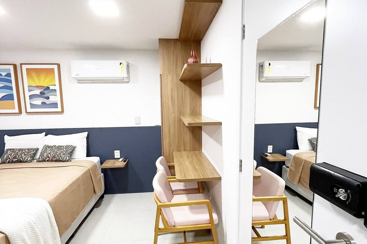 Un dormitorio con cama, escritorio, dos sillas, armario y espejo.