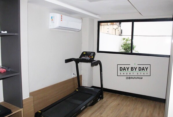 A room with a treadmill, a window with a view, and an air conditioning unit. - Bauten Aurea By DayByDay (Joao Pessoa)