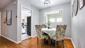 A dining area with a round table, floral-patterned chairs, and a view of the kitchen through an open doorway. - River Oaks Retreat- Walkable to Goodfellow AFB (San Angelo)