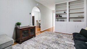 A living room with a dark wooden cabinet, a white bookshelf, and a patterned rug. - River Oaks Retreat- Walkable to Goodfellow AFB (San Angelo)