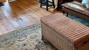 A cozy cabin interior with a wooden interior, a dining area with stools, a sofa, and a wicker ottoman. - Eastgate cottages on Mars Hill Mountain (Mars Hill)