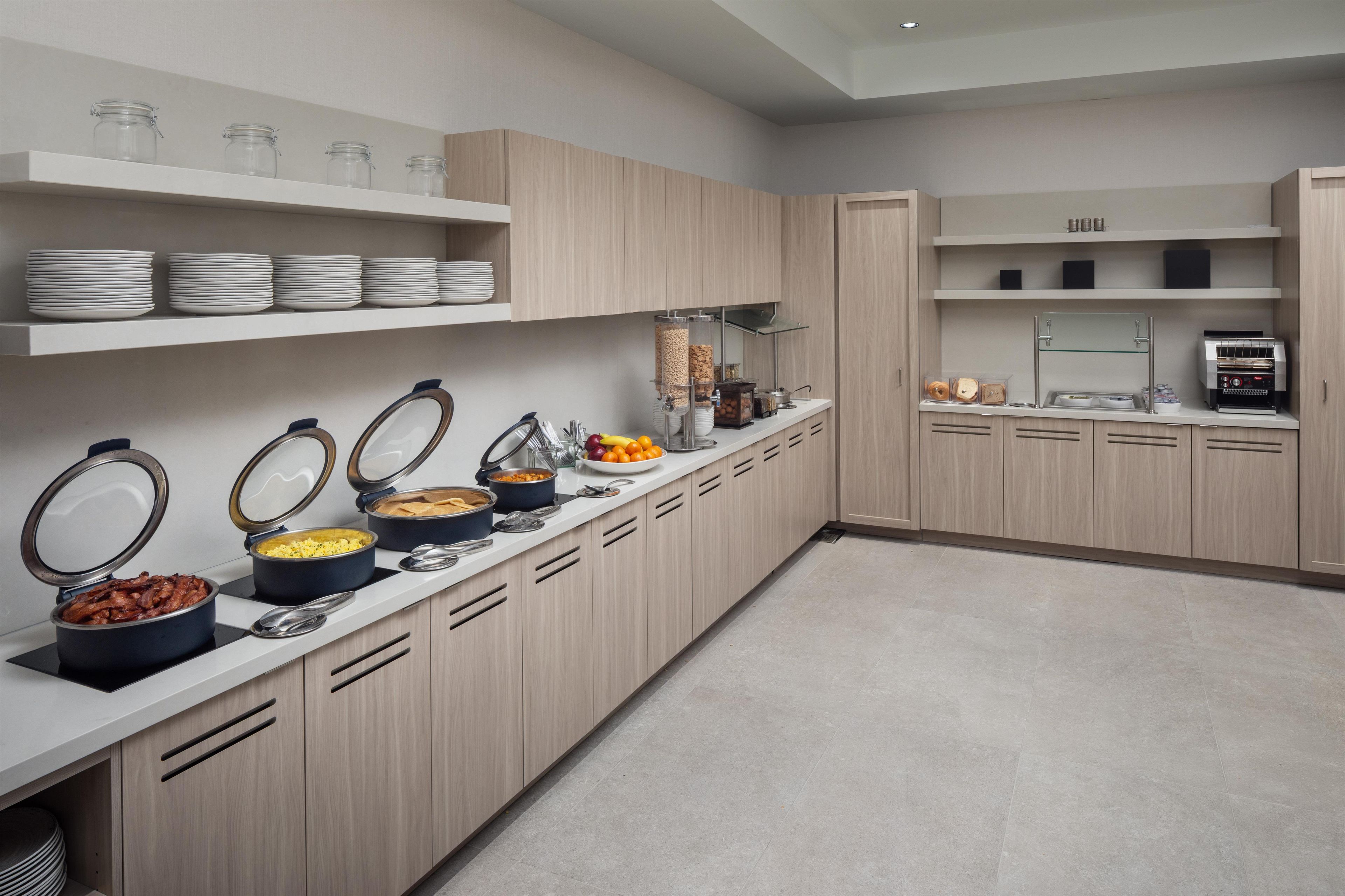 Een moderne keuken met inbouwapparatuur, een buffetopstelling en netjes geordende opslagplanken.