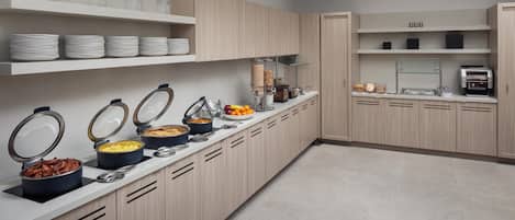 Uma cozinha moderna com eletrodomésticos embutidos, um espaço para buffet e prateleiras organizadas.