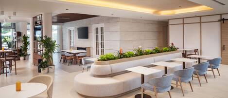 Un intérieur moderne avec un espace salon aux lignes courbes, des tables à manger et des chaises.