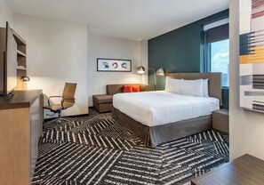 A modern hotel room with a large bed, a desk, a chair, and a desk lamp. - Hyatt House Destin (Destin)