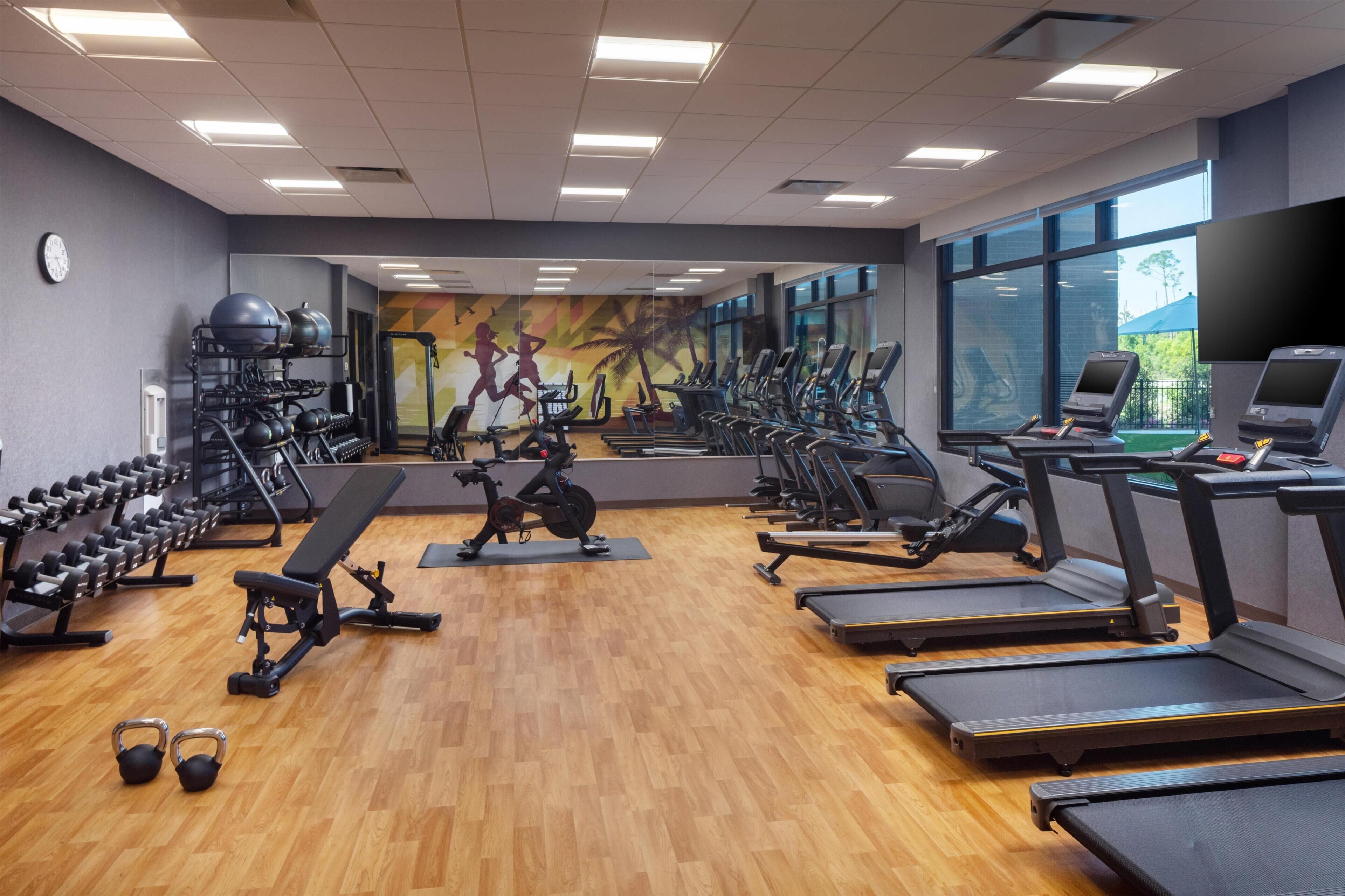 Een fitnessruimte met loopbanden, elliptische trainers en losse gewichten.