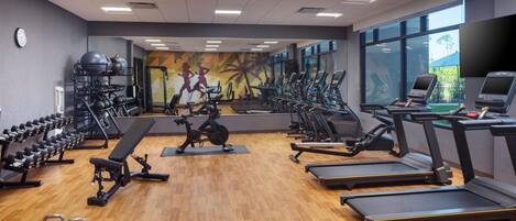 Un gimnasio con cintas de correr, elípticas y pesas libres.