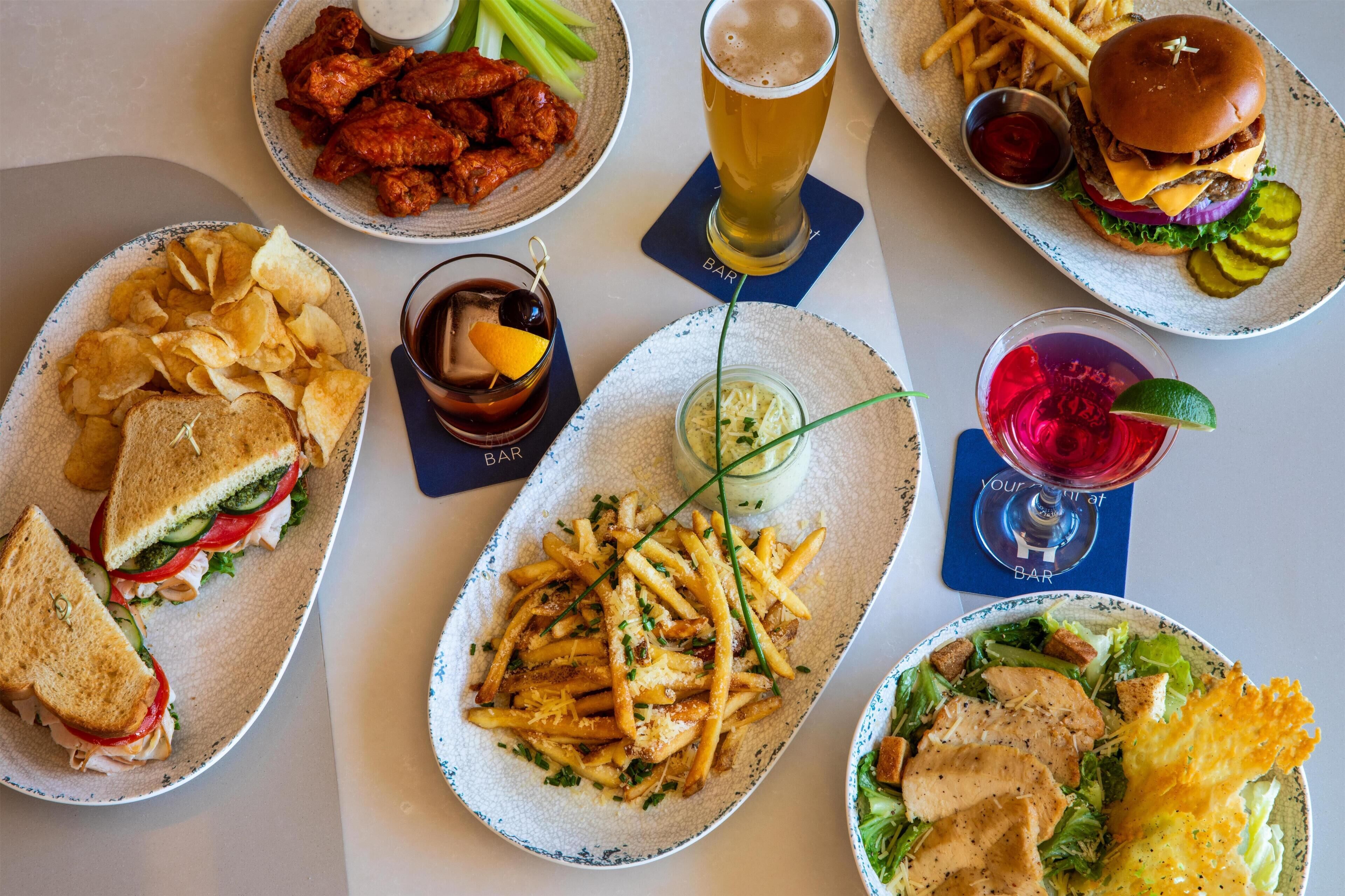 A variety of food items on a table, including sandwiches, fries, and a burger.