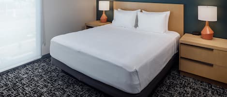 A hotel room with a large bed, two bedside tables with lamps, a window, and a dark wall.