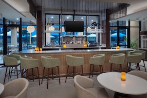 A bar area with a counter, bar stools, and a large window offering a view of the outdoors.