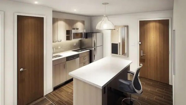 A modern kitchen with a central island, stainless steel appliances, and a pendant light. - Hyatt House Destin (Destin)