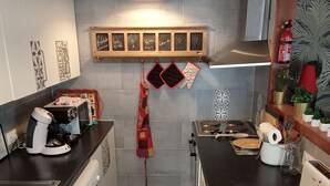 Une petite cuisine équipée d’une machine à café, d’un grille-pain et d’une serviette rouge accrochée au mur.