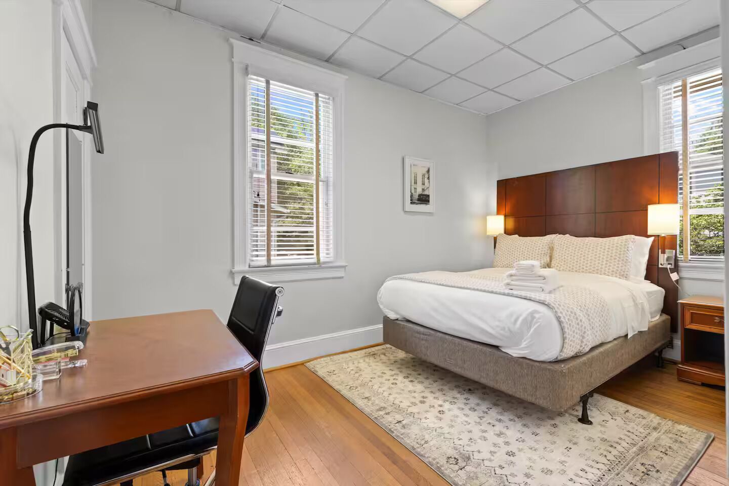 A bedroom with a bed, bedside tables, a desk, and a chair.