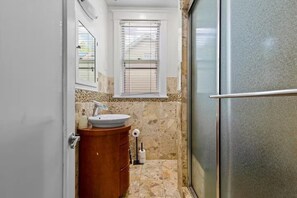 Un bagno con lavandino, mobile lavabo e zona doccia.