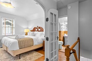 Un dormitorio con cama, mesita de noche, lámpara y ventana con persianas.