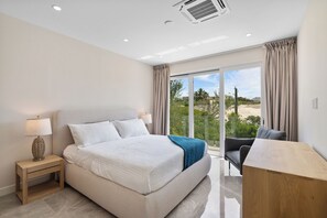 Ein modernes Schlafzimmer mit einem großen Bett, einem Schreibtisch und Blick ins Freie.
