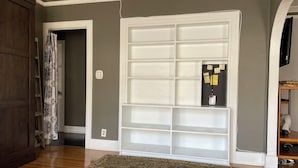 A room with a wooden floor, a patterned rug, a white door, and a white shelving unit with notes attached. - This property is no longer available. 1 Bedroom / 1 Bath Duplex near Melrose (Los Angeles)