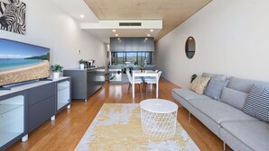 Un salon moderne comprenant un canapé, un téléviseur et un coin repas avec une table et des chaises.