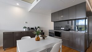 Une cuisine moderne avec des meubles gris, un plan de travail blanc et un coin repas comprenant une table et des chaises blanches.