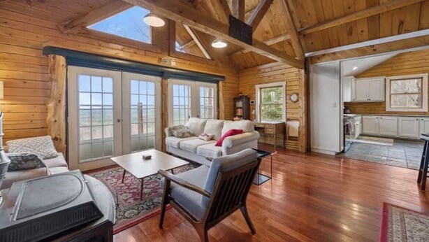 Une cabane en bois spacieuse, dotée d’un salon confortable avec un canapé, une table basse et une cheminée.